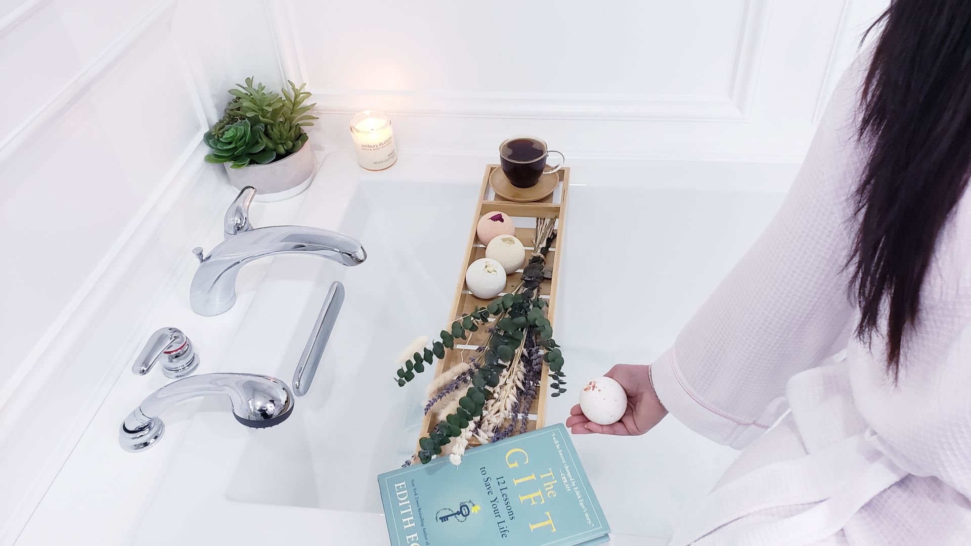 Woman displaying natural bath bombs - handmade and luxurious natural bath products for women in a bathtub