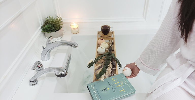 Woman relaxing in a bathtub with bath bombs and bubbles, creating a soothing and calming atmosphere for self-care and relaxation in a spa-like bathroom.