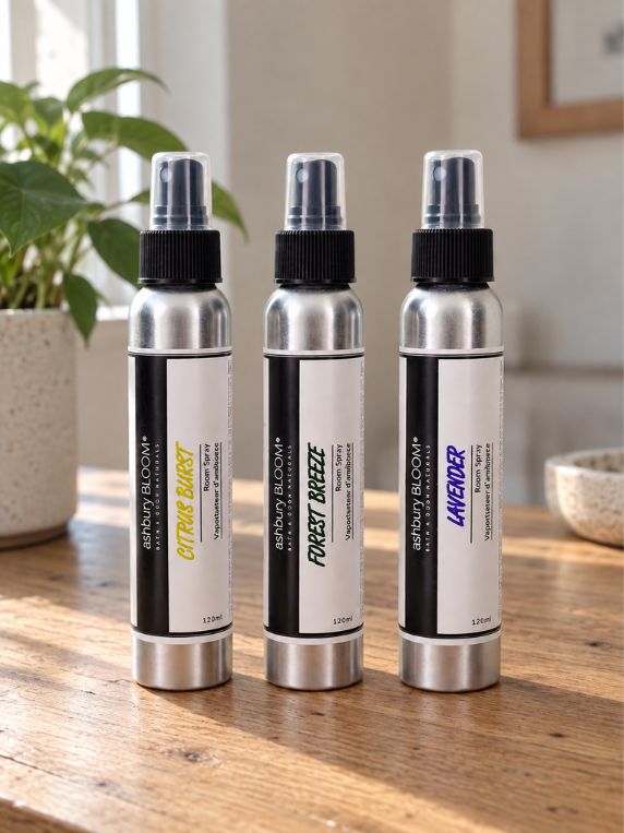 Ashbury Bloom Citrus Burst, Forest Breeze and Lavender room sprays displayed together in a natural home setting.
