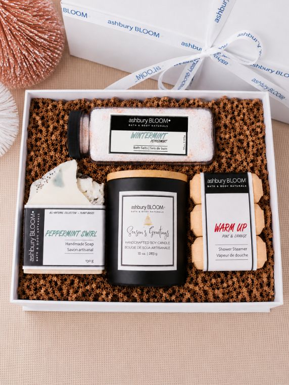 Ashbury Bloom Holiday Gift Box featuring Wintermint Bath Salts, Peppermint Swirl Handmade Soap, Season’s Greetings Soy Candle, and Warm Up Shower Steamers in a white gift box with festive ribbon.