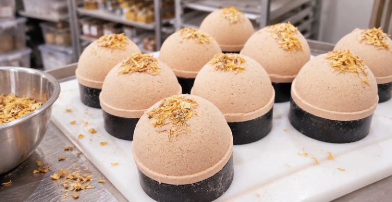 Freshly pressed handmade bath bombs with botanical toppings resting in moulds during production at ashbury BLOOM•